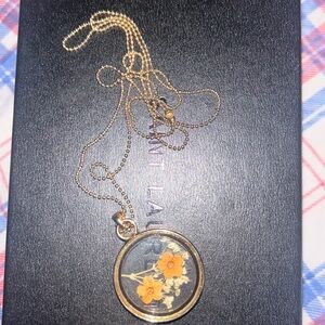 Gold necklace with a charm on it with flowers in it